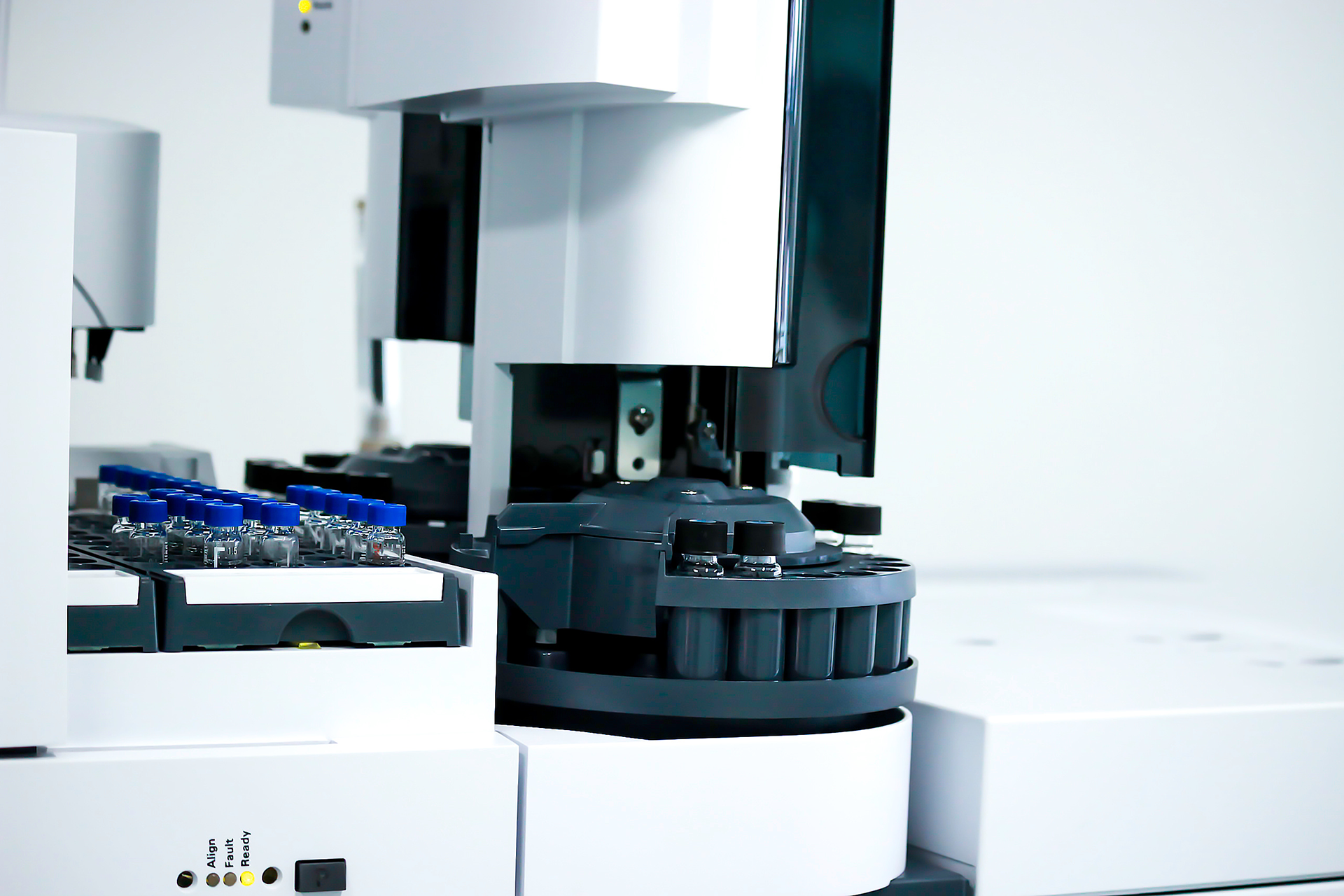 A stack of refurbished LC-MS and GC-MS equipment with glass bottles on top, connected by tubes to a black device with a blue stripe.